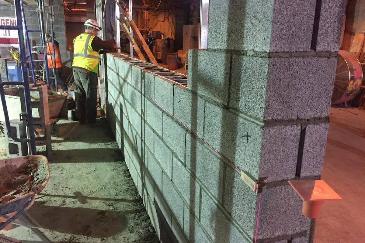 Maurer errichtet eine Wand aus Betonsteinen